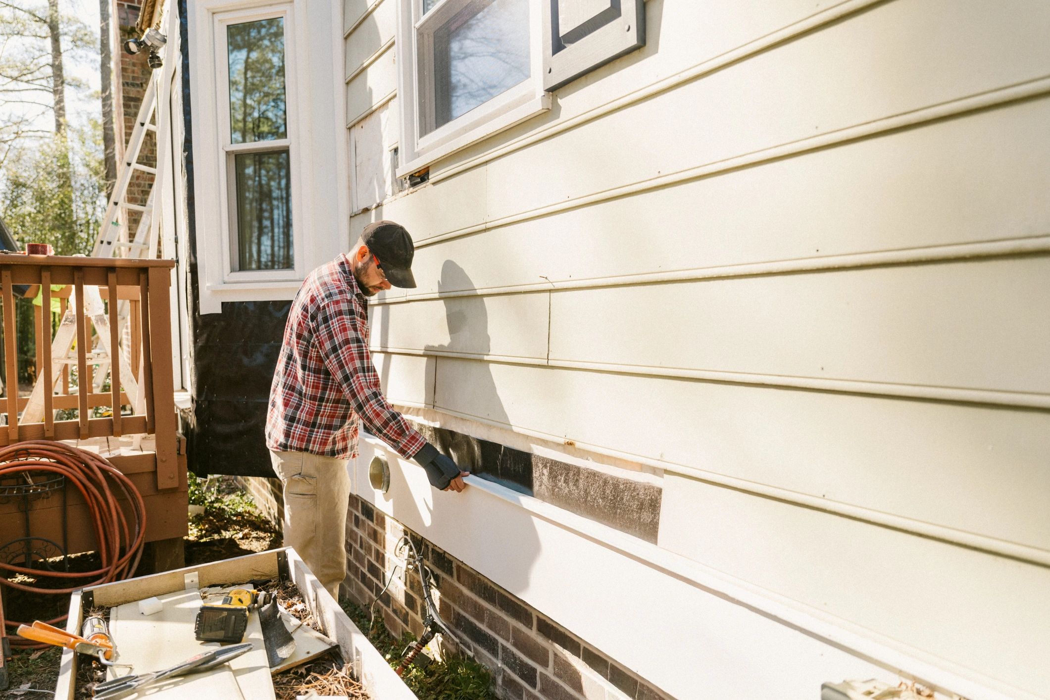 Technician working on the exterior of a home to address potential pest entry points
